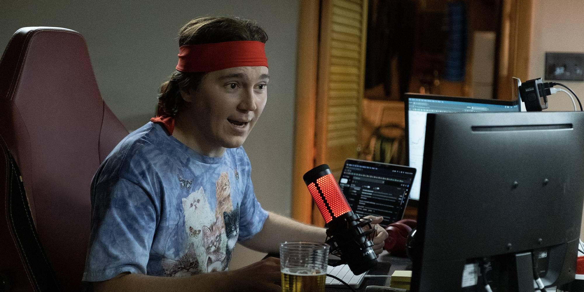 Paul Dano looking at a computer screen and sitting at the desk in Dumb Money.