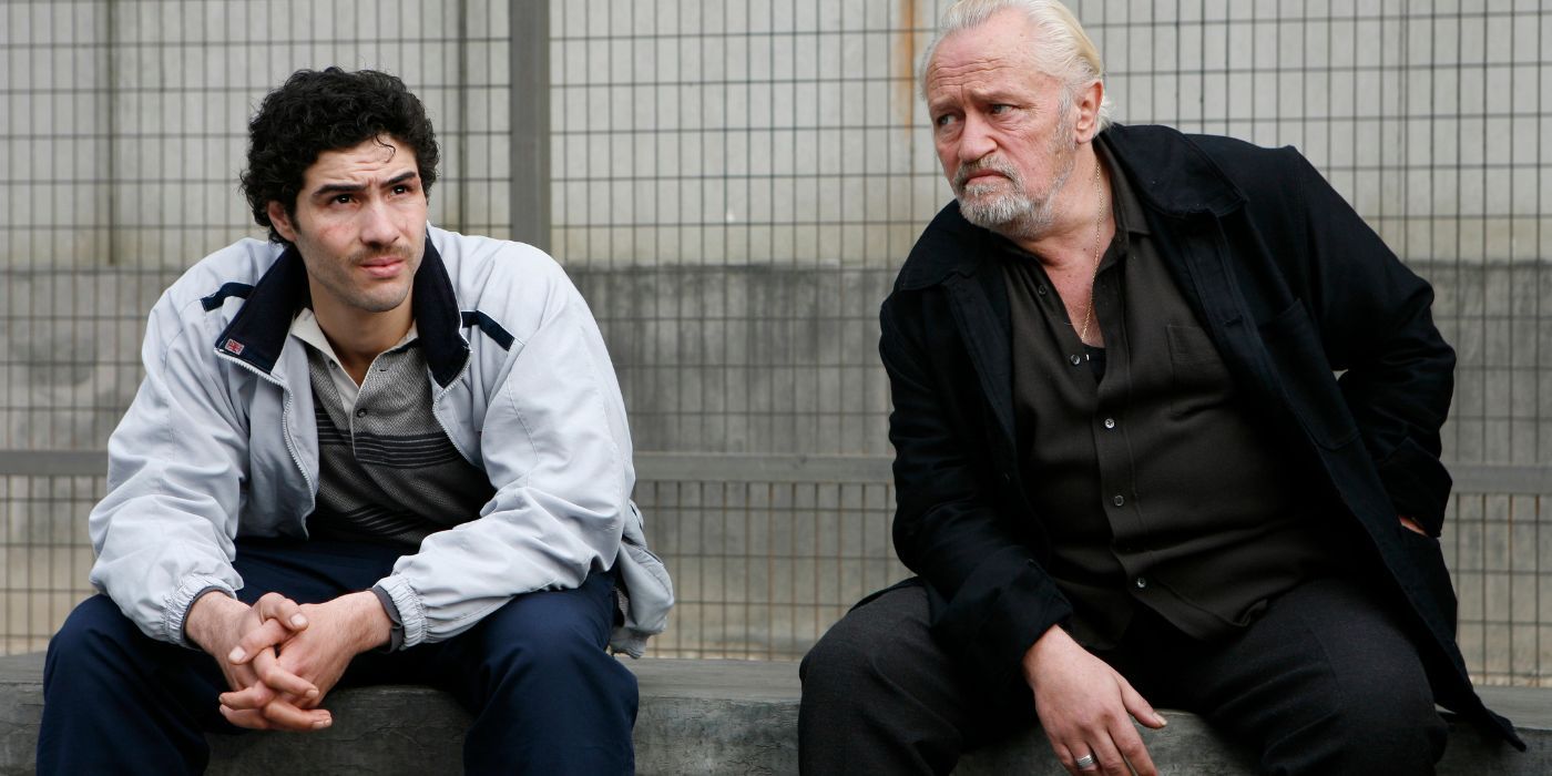 Niels Arestrup and Tahar Rahim sitting next to each other on a bench in A Prophet