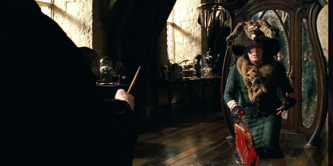 Professor Snape (Alan Rickman) stands in a green dress with a handbag and a hat.
