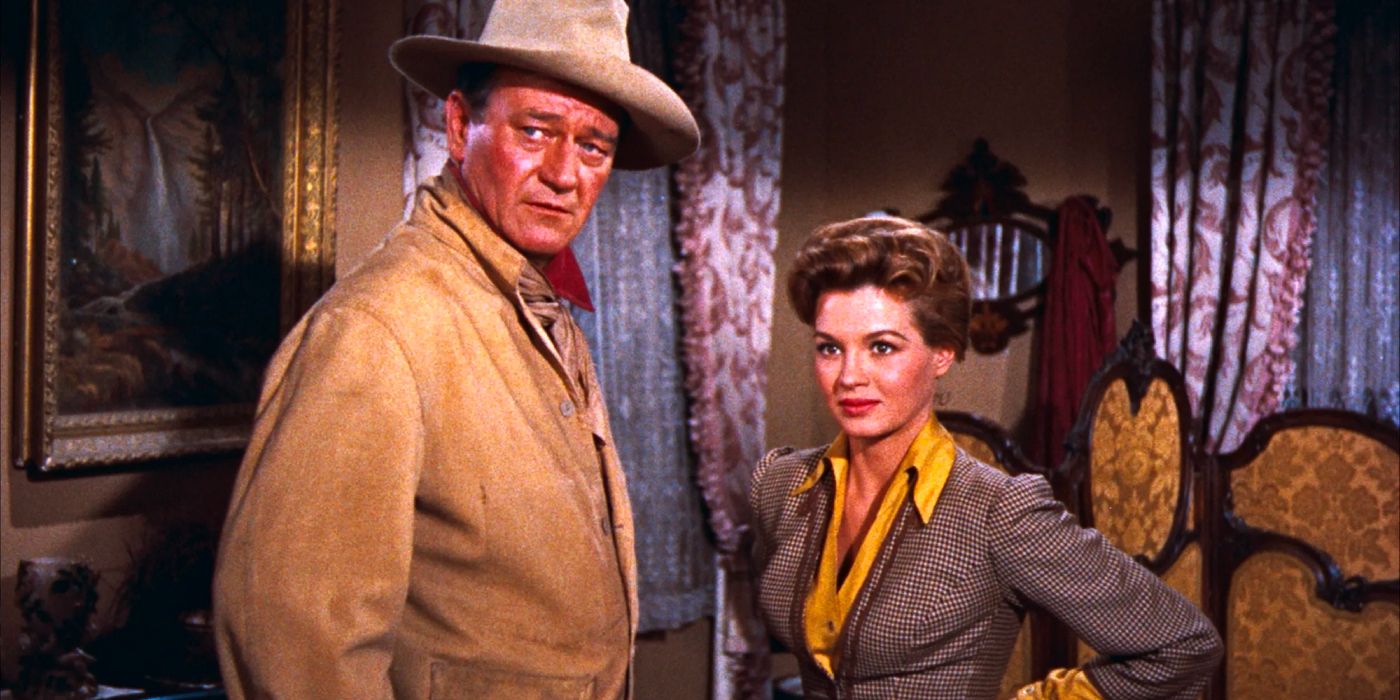 John Wayne and Angie Dickinson stand in a hotel room of a saloon in 'Rio Bravo' (1959)