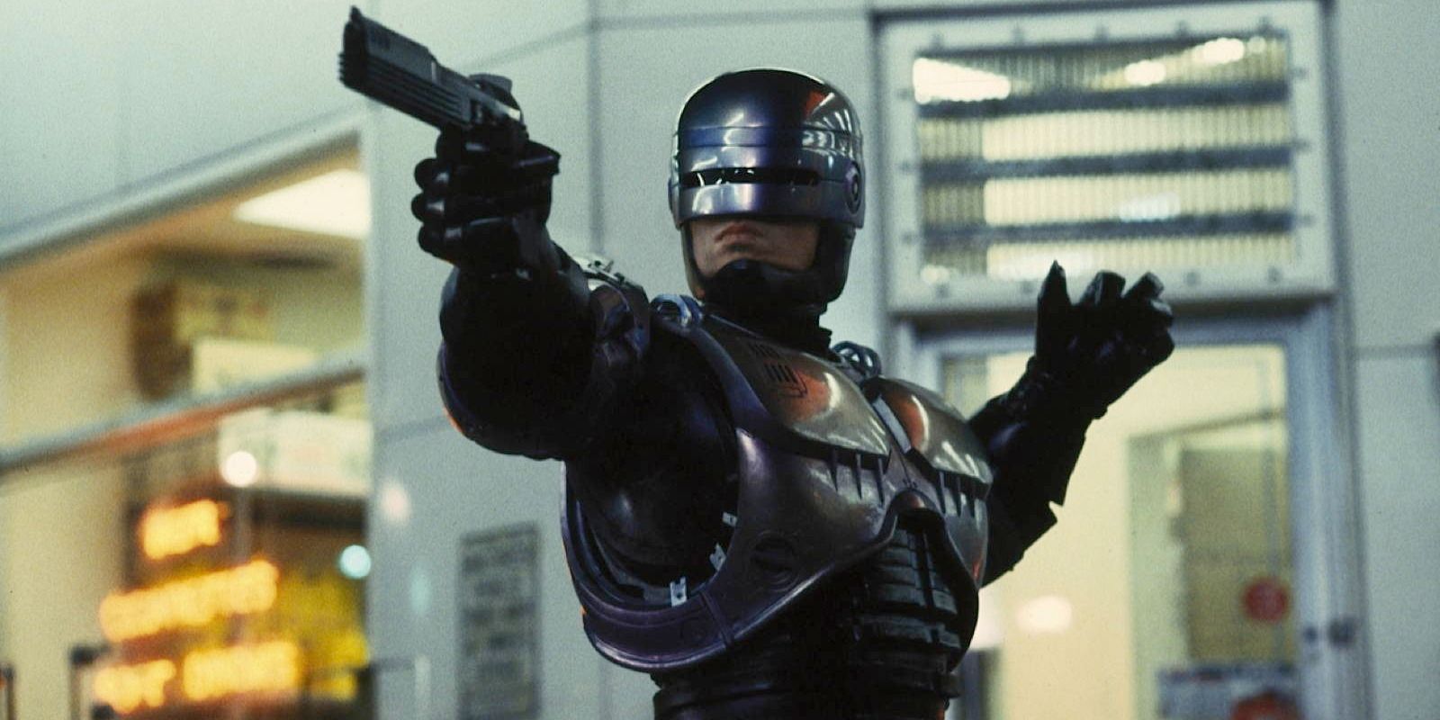 Robocop (Peter Weller) aiming a pistol at a perpetrator off-screen in 'Robocop'