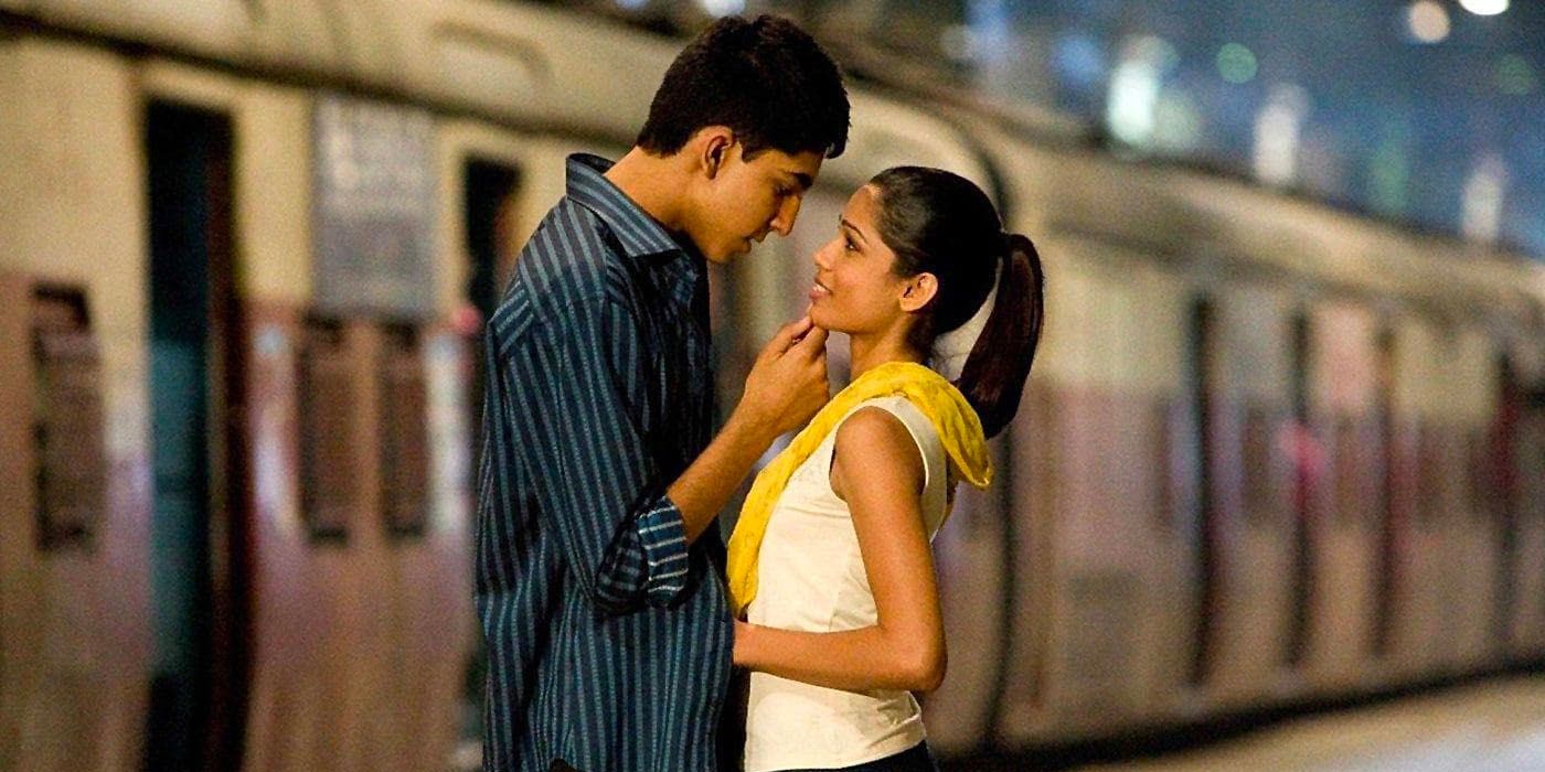 Dev Patel and Frieda Pinto stand at the train station in an intimate embrace in a scene from Slumdog Millionaire