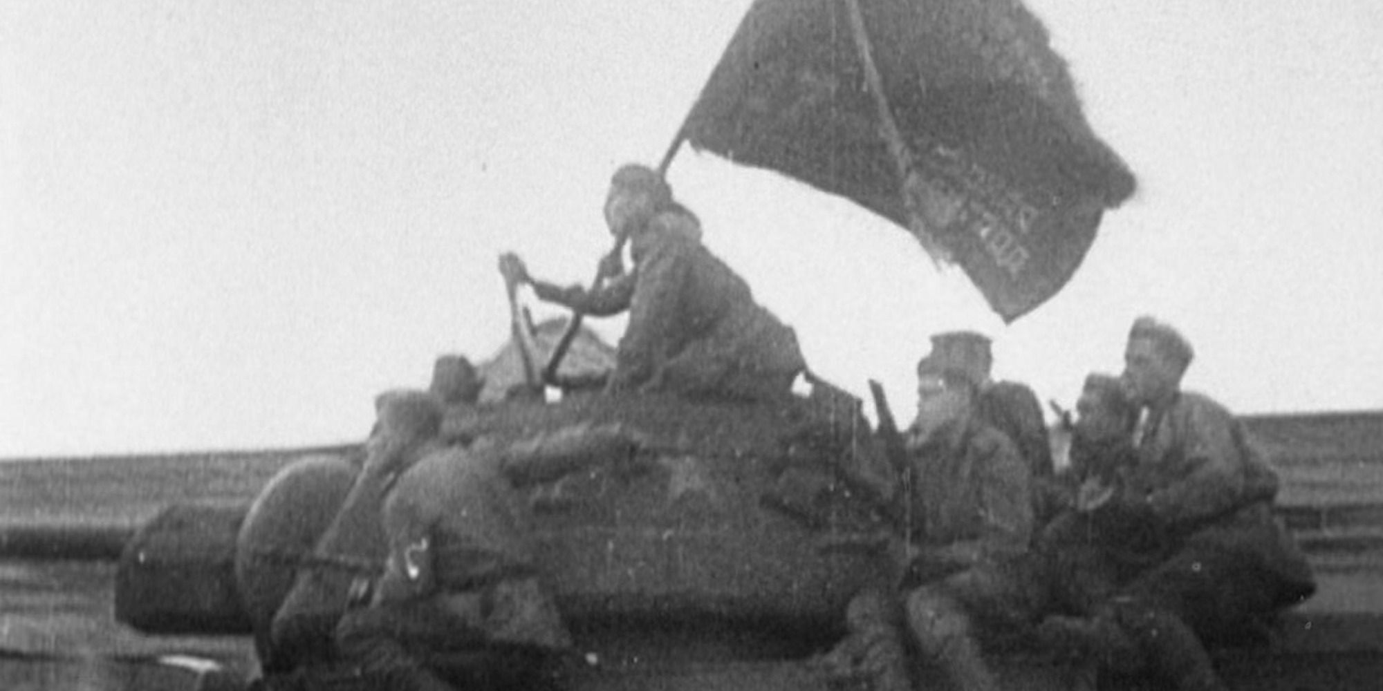 soldiers with a flag on top of a tank in WWII