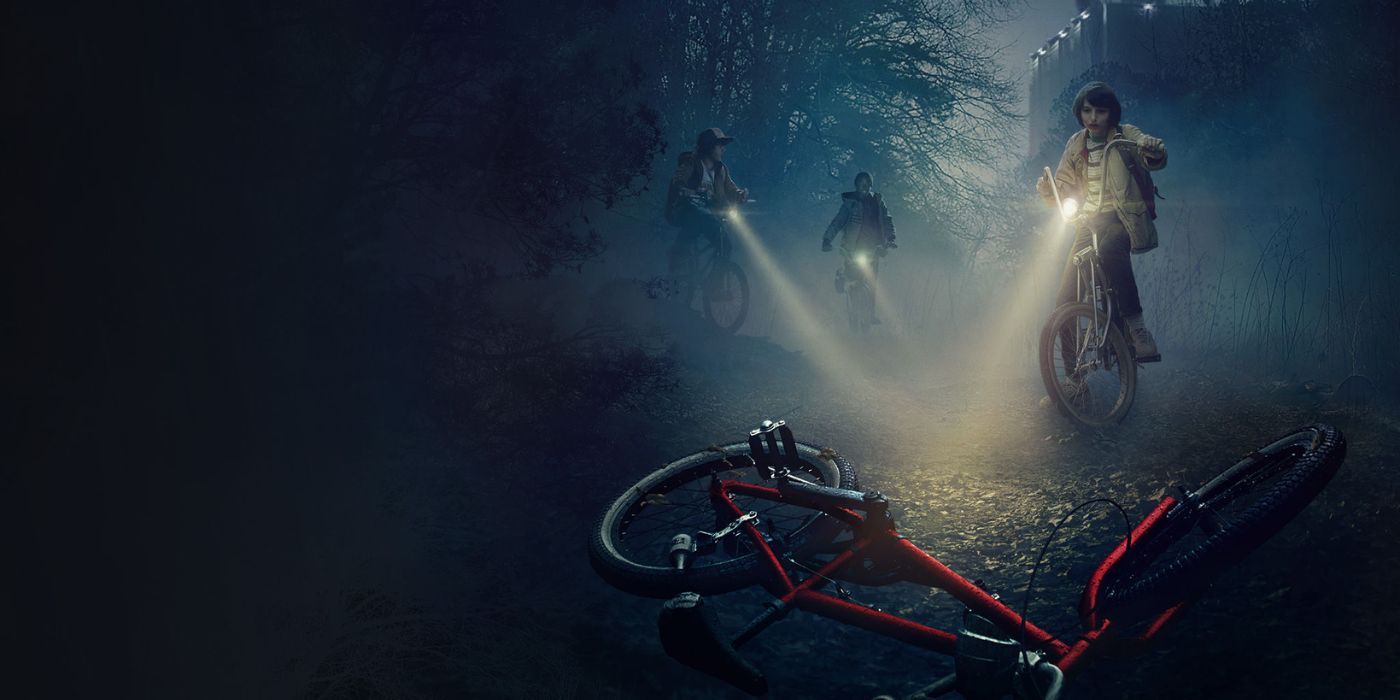Kids on bikes aim their flashlights at a ruined bicycle in the woods