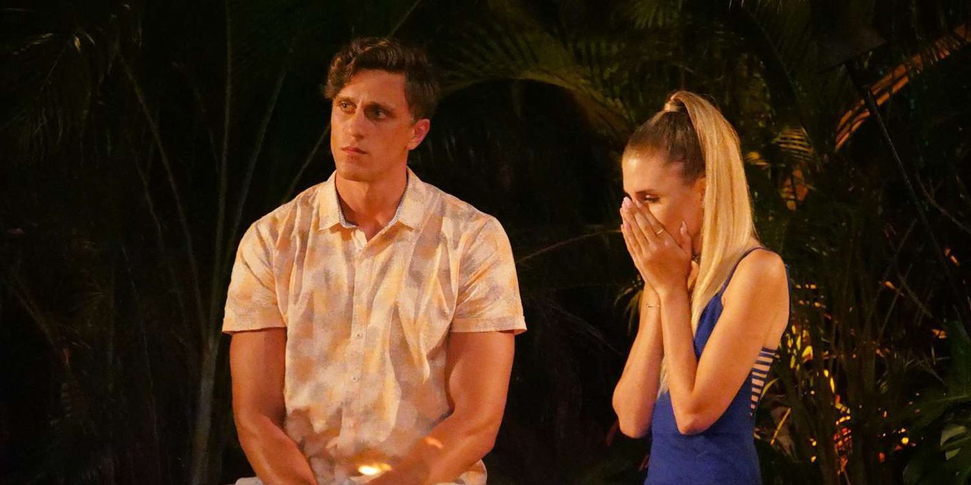 Evan and Kaci sitting at a bonfire on Temptation Island, her with her face in her hands.