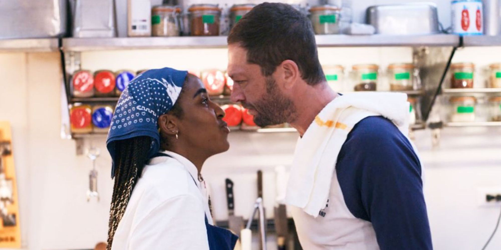 Ayo Edebiri and Ebon Moss Bachrach stand very close face to face in a kitchen in The Bear.