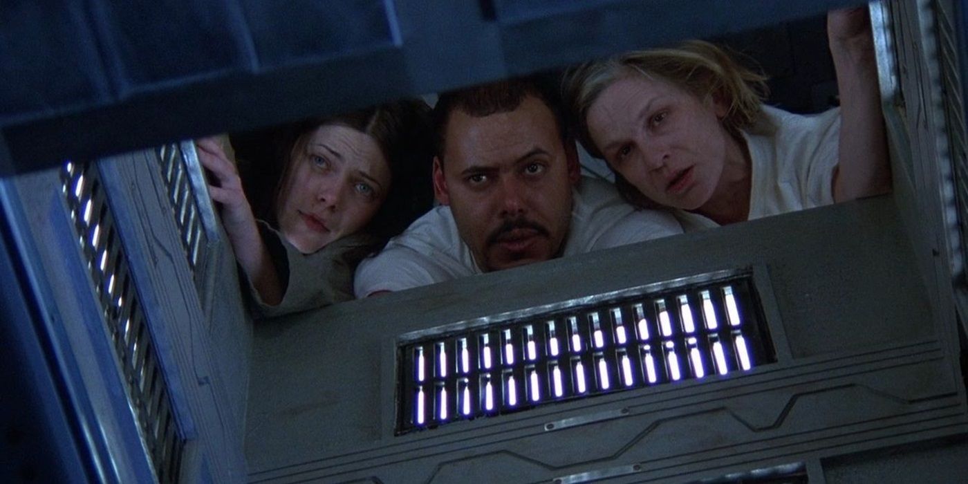 Nicole de Boer, Nicky Guadagni, and Maurice Dean Wint looking through a box in Cube (1997)