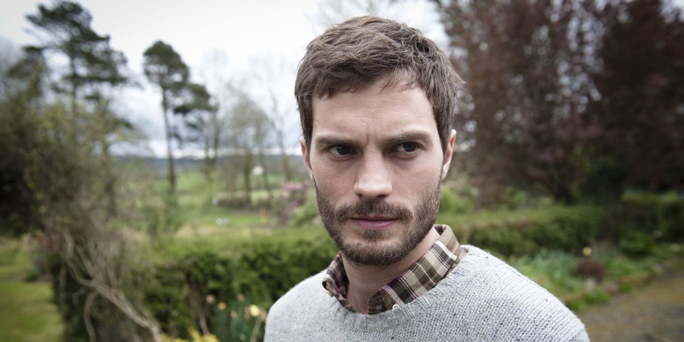 Jamie Dornan as Paul Spector standing on a rural road and looking to the right in The Fall