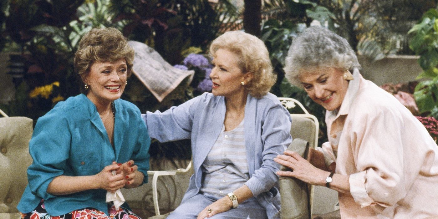 Bea Arthur as Dorothy, Rue McClanahan as Blanche, and Betty White as Rose sit on the couch in The Golden Girls