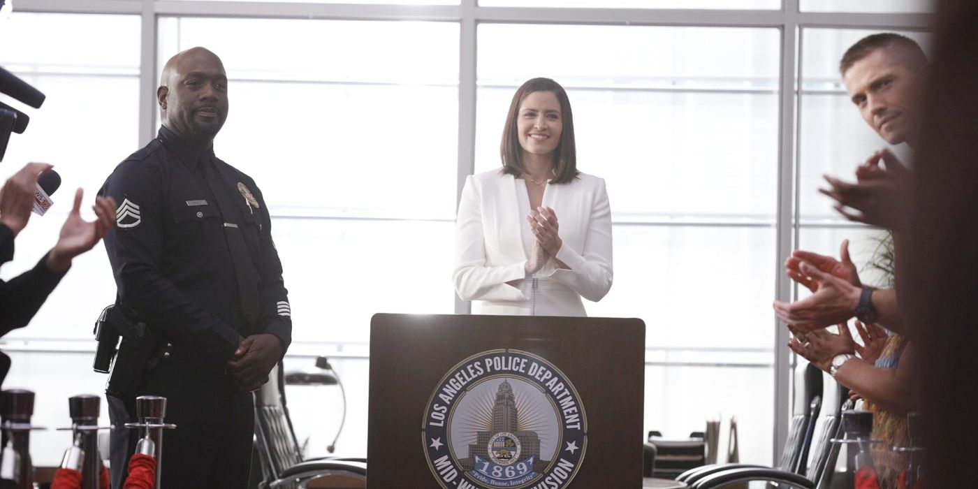 Richard T. Jones & Mercedes Mason as Wade Grey & Zoe Andersen, smile & applaud at a press conference.