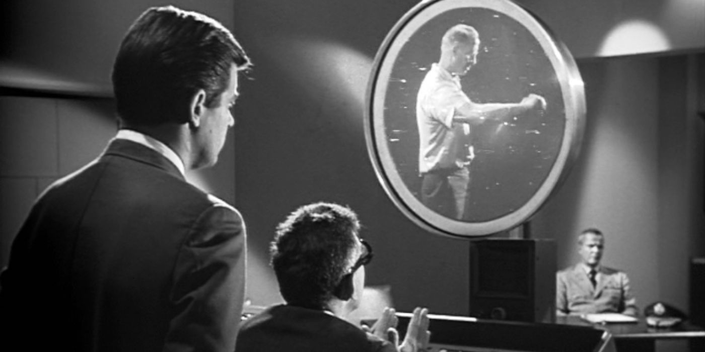 two men in black watch a monitor