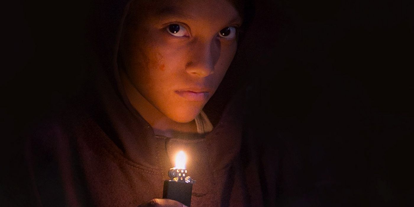 A child holds a burning lighter and looks at the camera in the film Tigers Are Not Afraid