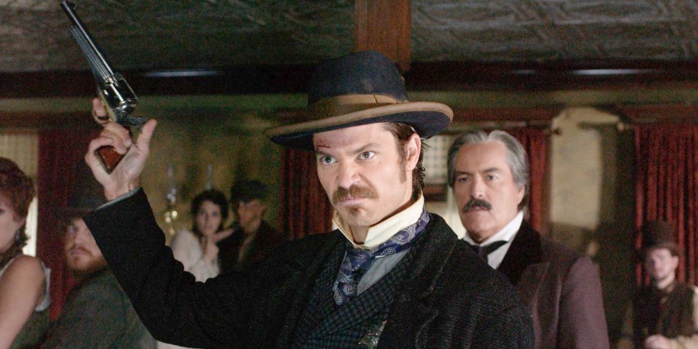 Timothy Olyphant as Seth Bullock, looking angry and aiming his pistol towards the roof in Deadwood