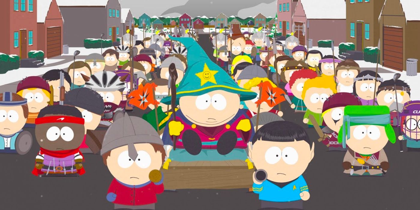 Cartman is carried through the streets of South Park on a throne while a legion of dressed-up kids follow him.