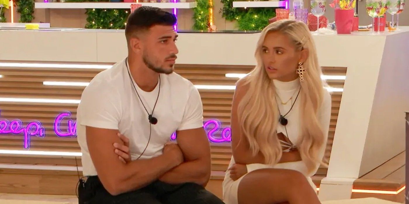 Tommy & Molly-Mae talk on a chair with a neon bar filled with drinks behind them in Love Island UK