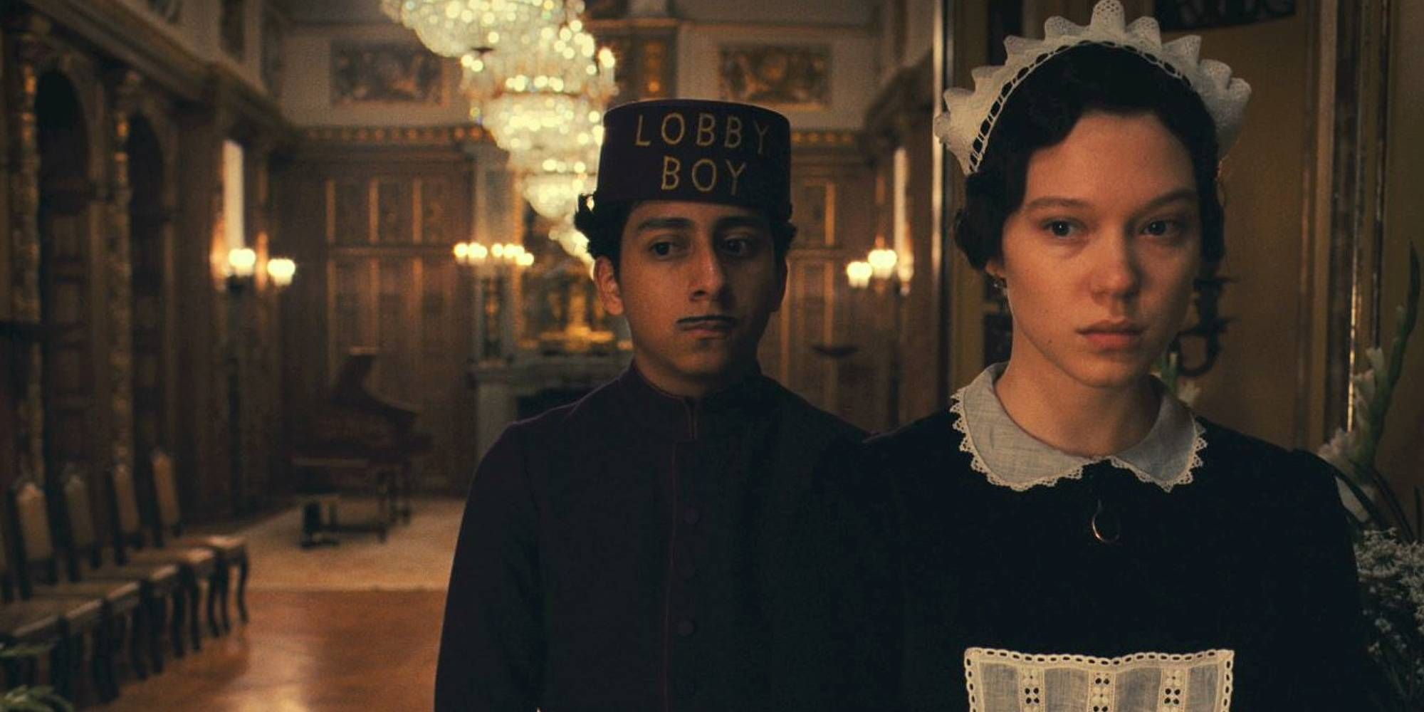 Tony Revolori standing behind Léa Seydoux in The Grand Budapest Hotel.
