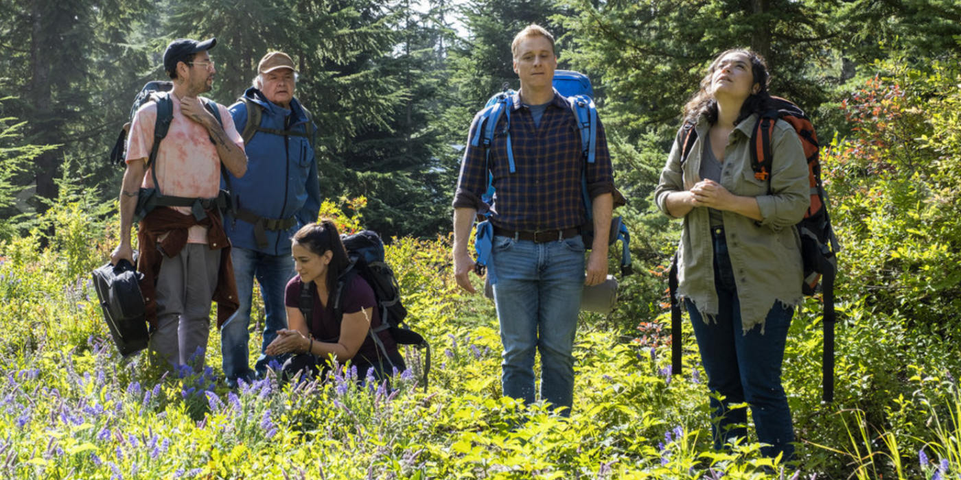 Harry and crew wearing backpacks in the woods in Resident Alien