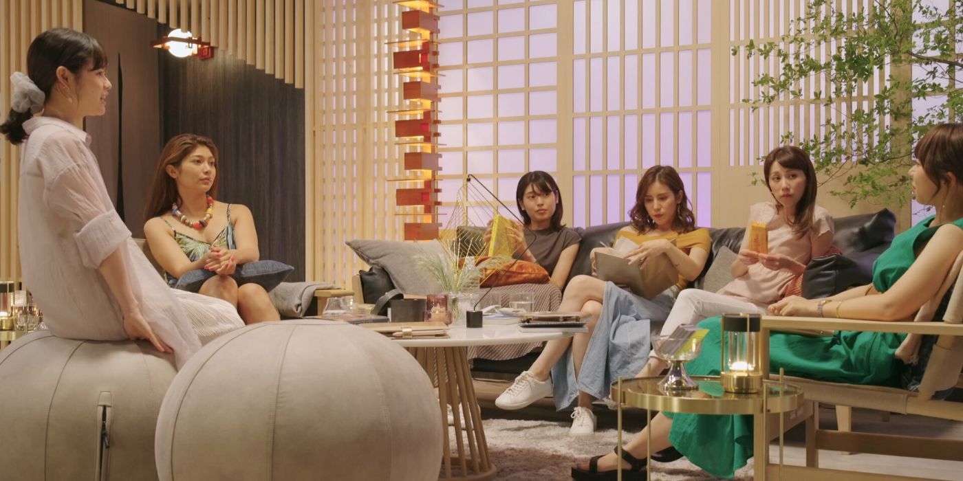 Female contestants of 'Love is Blind: Japan' sitting next to each other and having a conversation at the lounge.