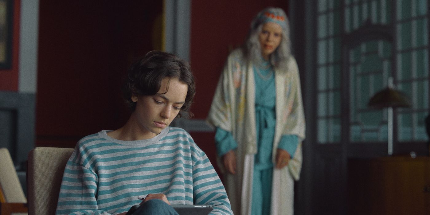 Brigette Lundy-Paine as Riley drawing in a chair while Anabela Moreira as Amelia lurks behind in the corner of the room in a still from Amelia'a Children.
