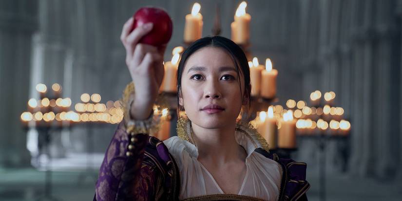 Jess Hong as Jin Cheng holding up an apple in a candlelit church in episode 103 of '3 Body Problem.'