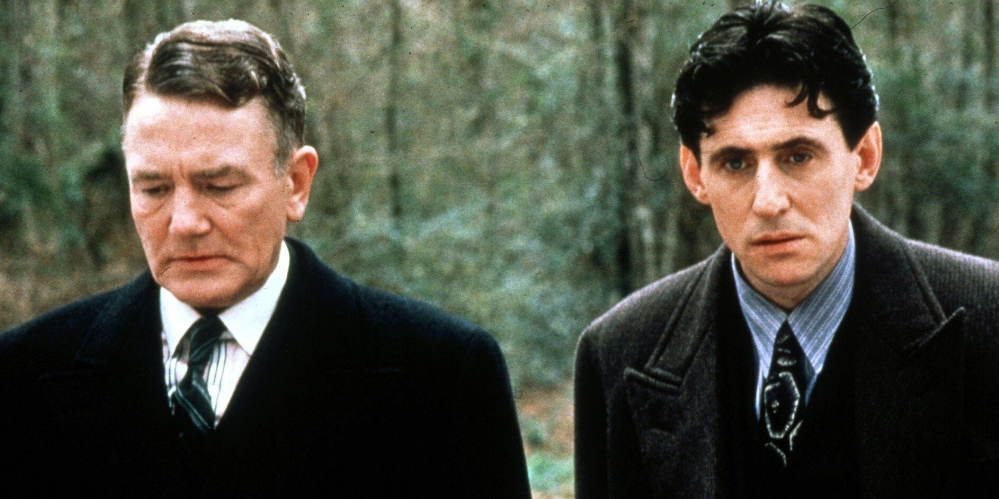 Albert Finney standing next to Gabriel Byrne in the woods in Miller's Crossing (1990)
