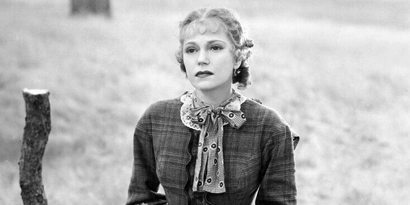 woman in old Western clothes sitting seriously in a field