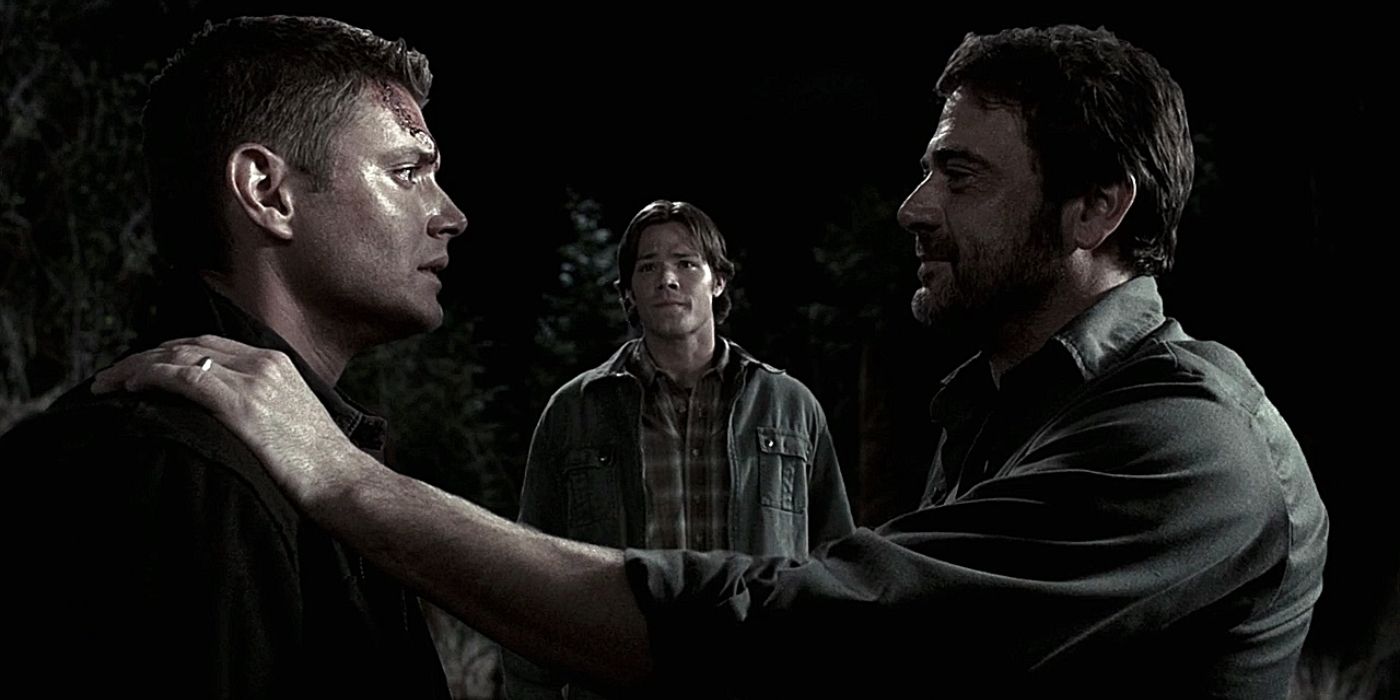 John Winchester's spirit embraces Dean while Sam stands in the background watching on.
