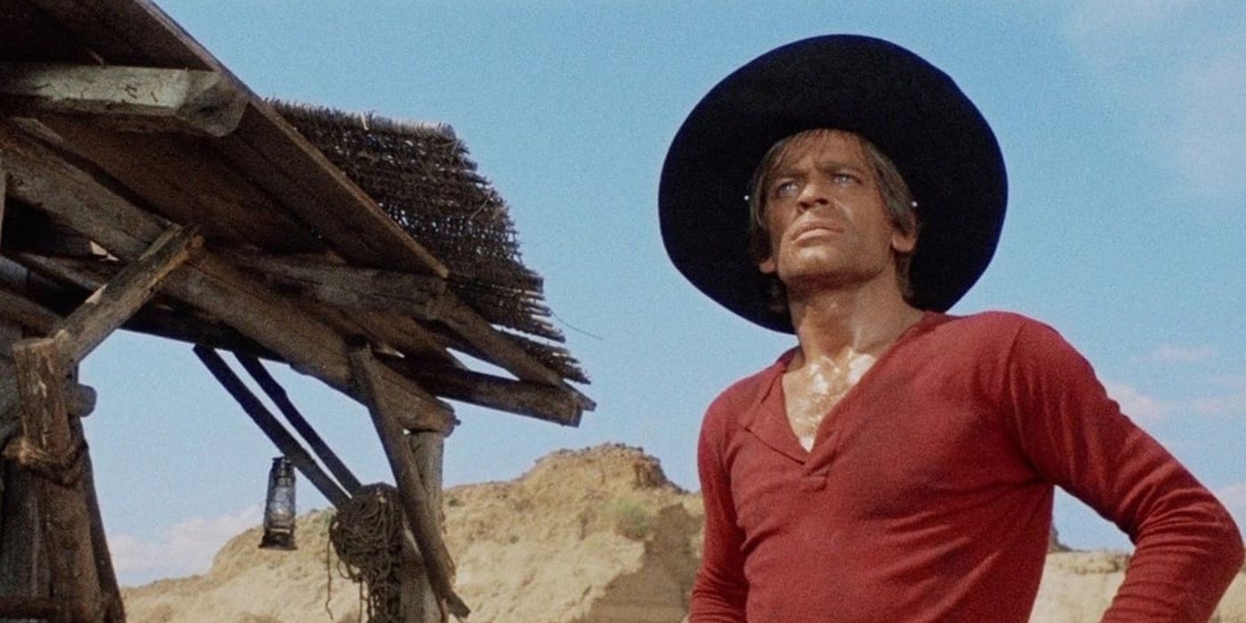Klaus Kinski as Gary-Hamilton wears a hat and stands near a shack in the desert in And God Said To Cain.