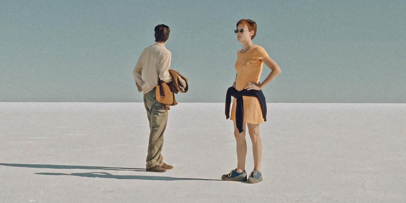 A woman in a yellow dress and a man in a shirt and trousers holding his jacket stand in the salt plains looking around at the vast nothingness in 'August 32nd on Earth' (1998)