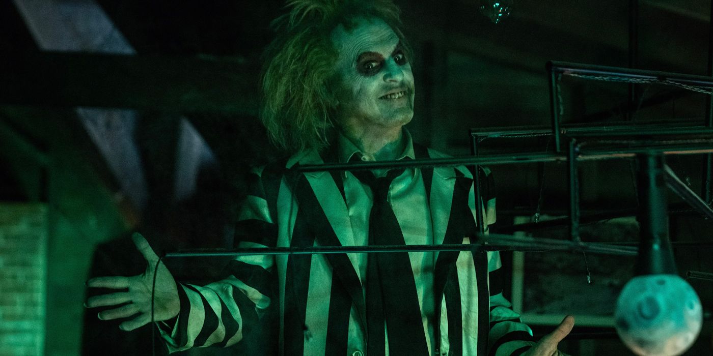 Michael Keaton as Betelgeuse standing with his arms out in Beetlejuice Beetlejuice