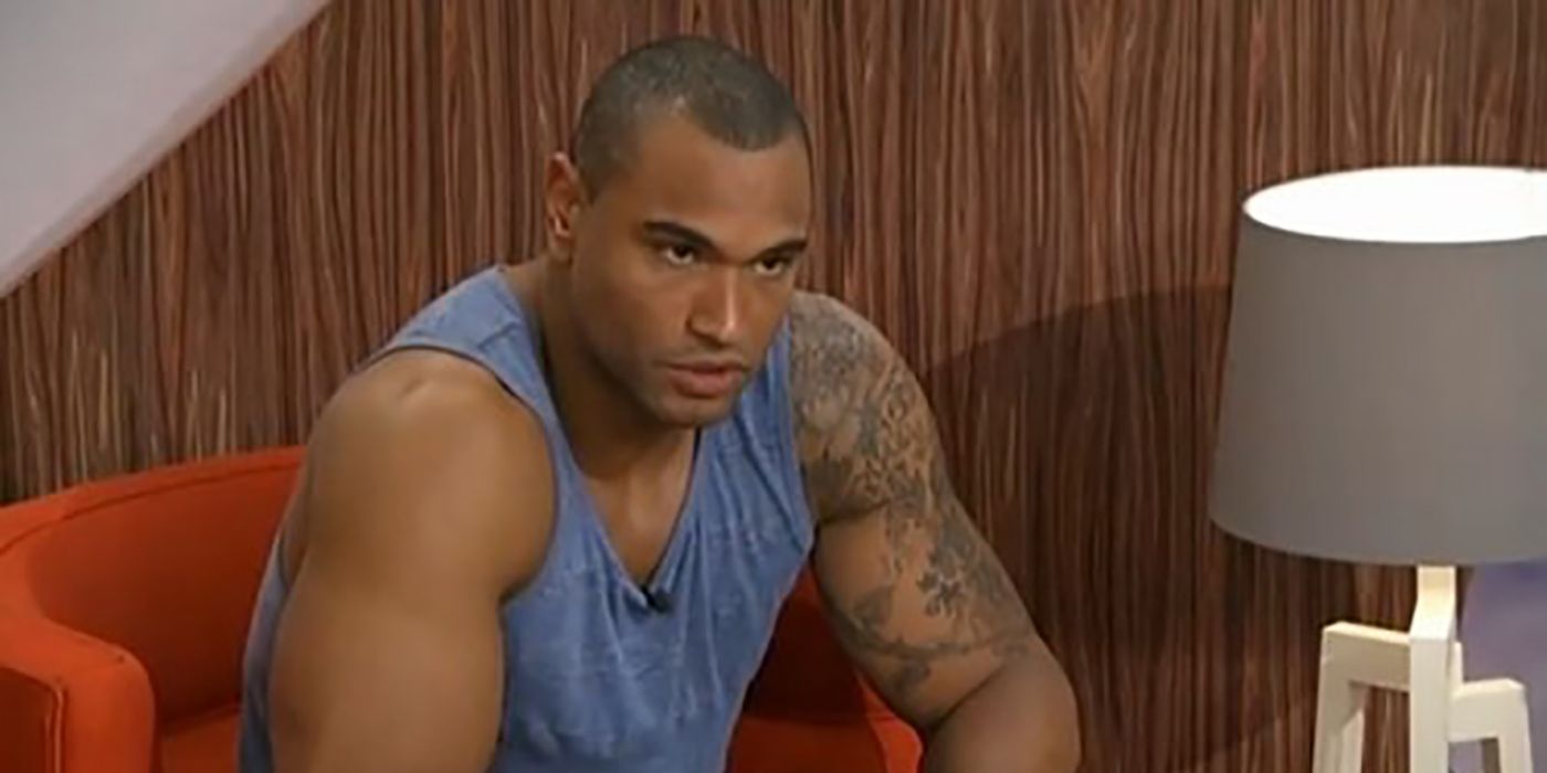 Devin from Big Brother sitting on a chair wearing a tank top, looking angry.