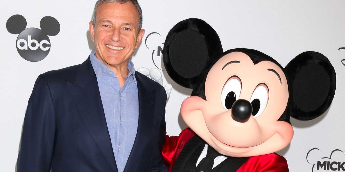 Bob Iger standing with Mickey Mouse on a red carpet