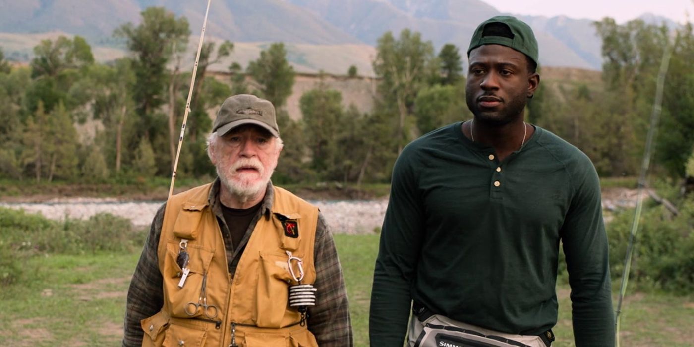 Brian Cox y Sinqua Walls caminan por un campo con aparejos de pesca en 