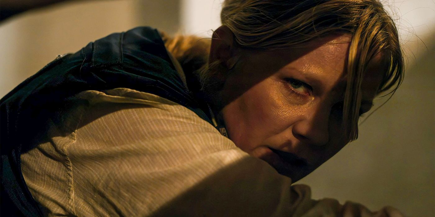 Kirsten Dunst as Lee looking out at a violent scene from the shadows in Civil War.