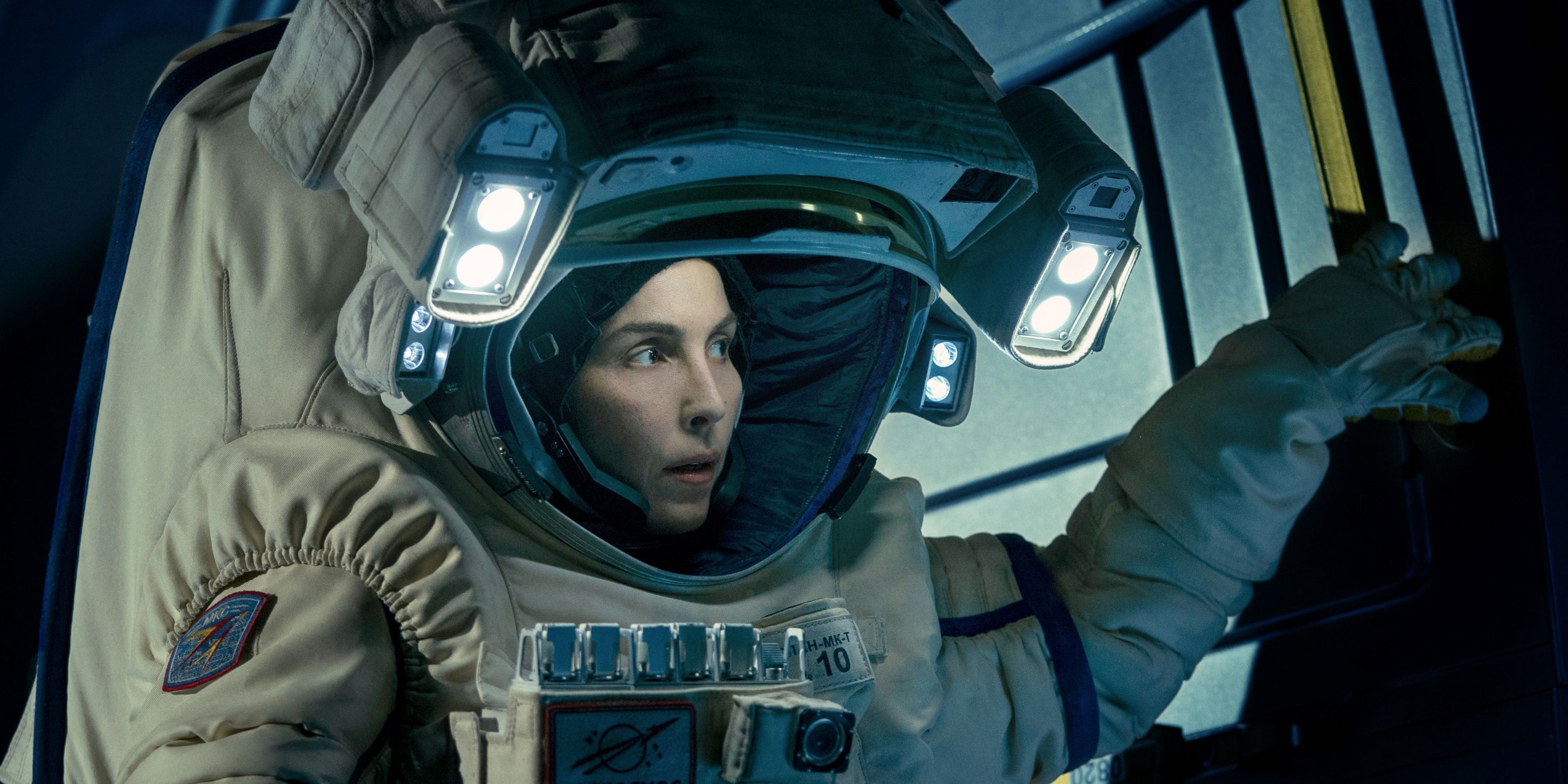 Noomi Rapace as Jo Ericsson in a space suit looking around suspiciously in Constellation
