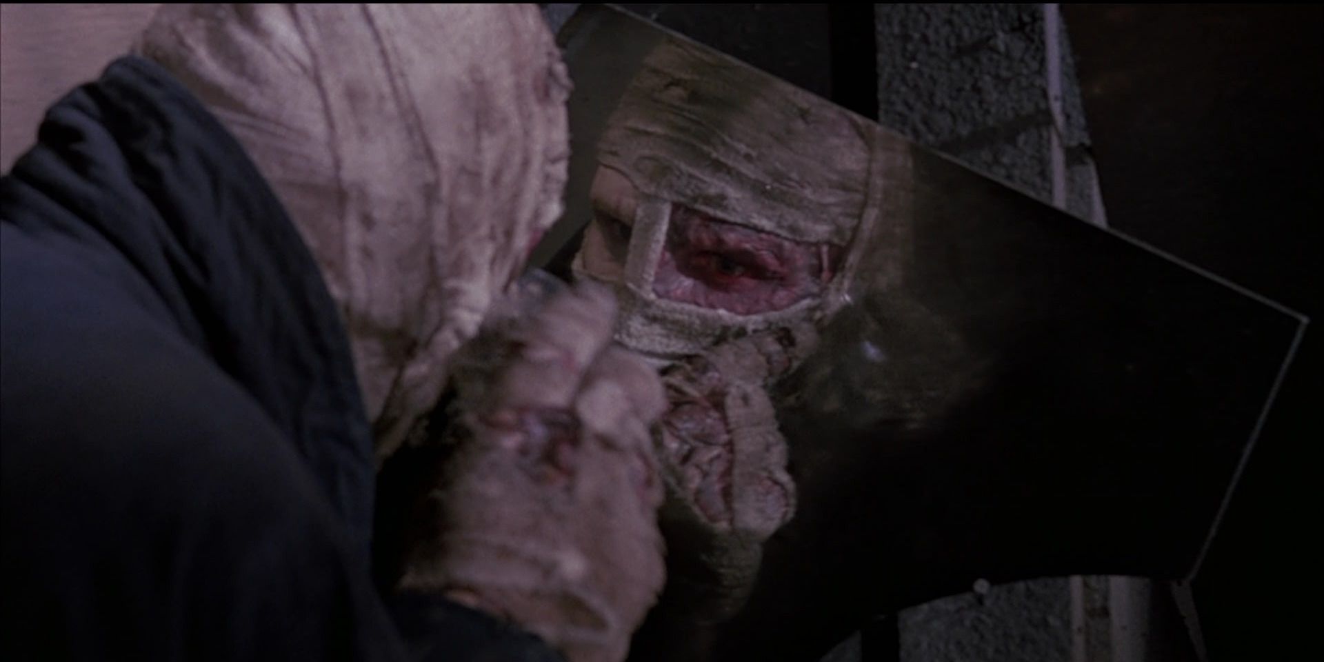 Liam Neeson sees his scarred form in the reflection of broken glass in Sam Raimi's Darkman