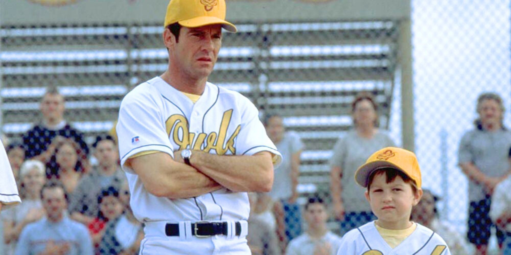 Dennis Quaid standing with arms folded across his chest next to Angus T. Jones in The Rookie (2002)