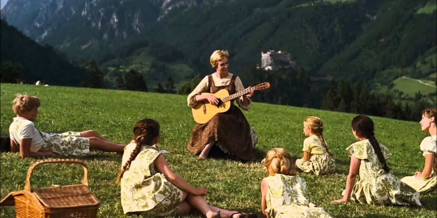 Maria plays guitar and sings surrounded by children in a meadow in The Sound of Music