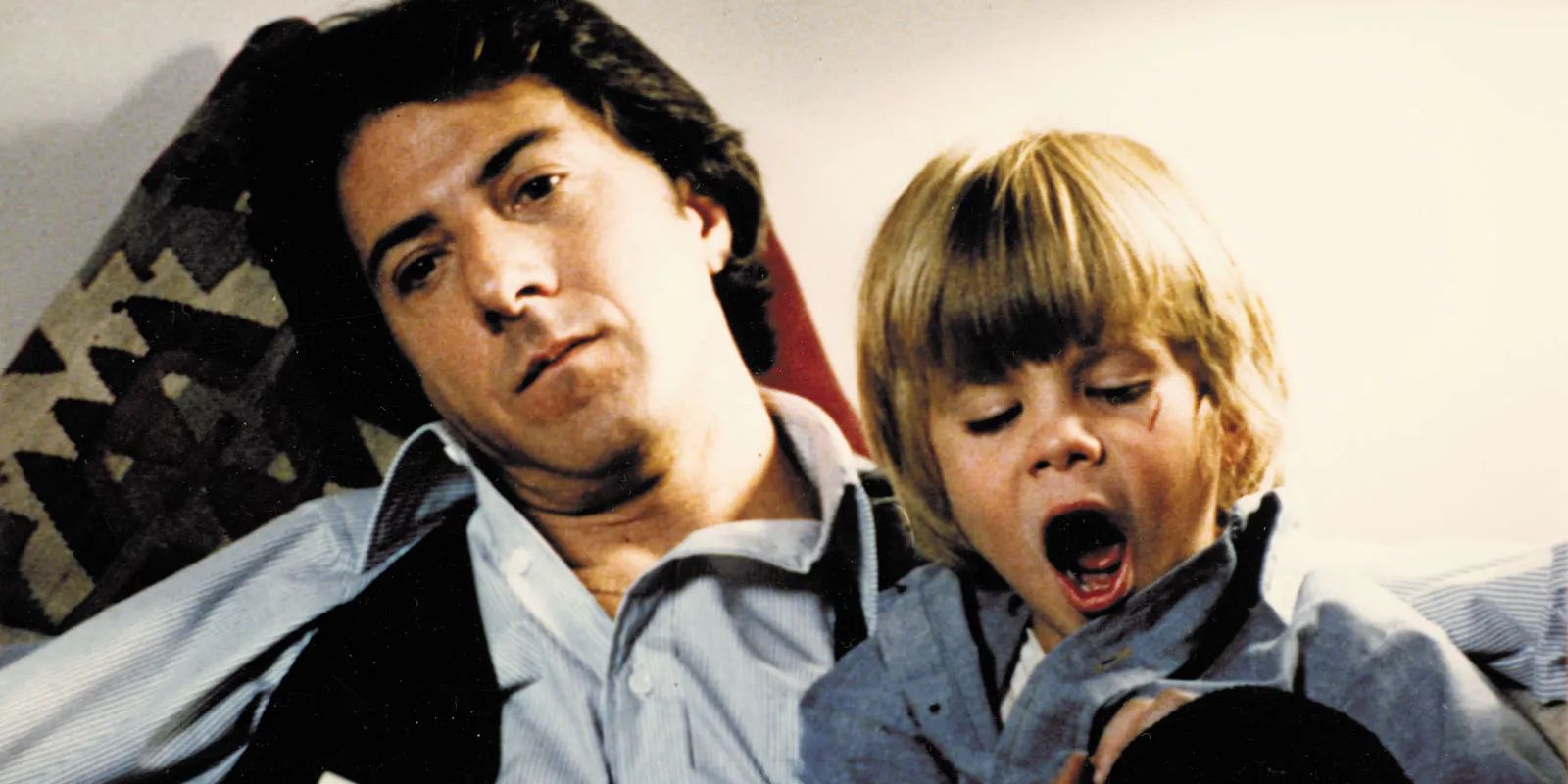 Ted Kramer (Dustin Hoffman) looks bored while Billy (Justin Henry) yawns in his lap in Kramer vs. Kramer