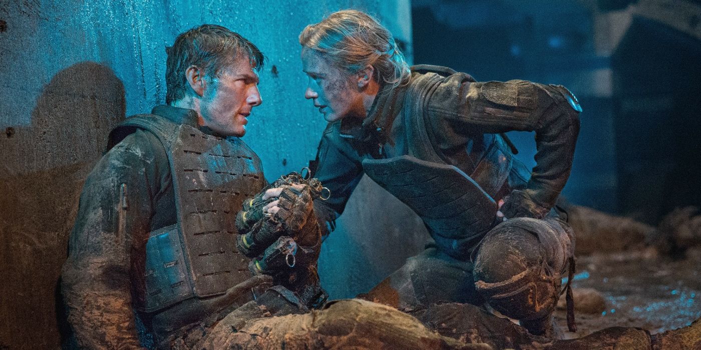 Tom Cruise and Emily Blunt as William Cage and Rita Vrataski, looking intensely at each other while Cage holds explosives in Edge of Tomorrow