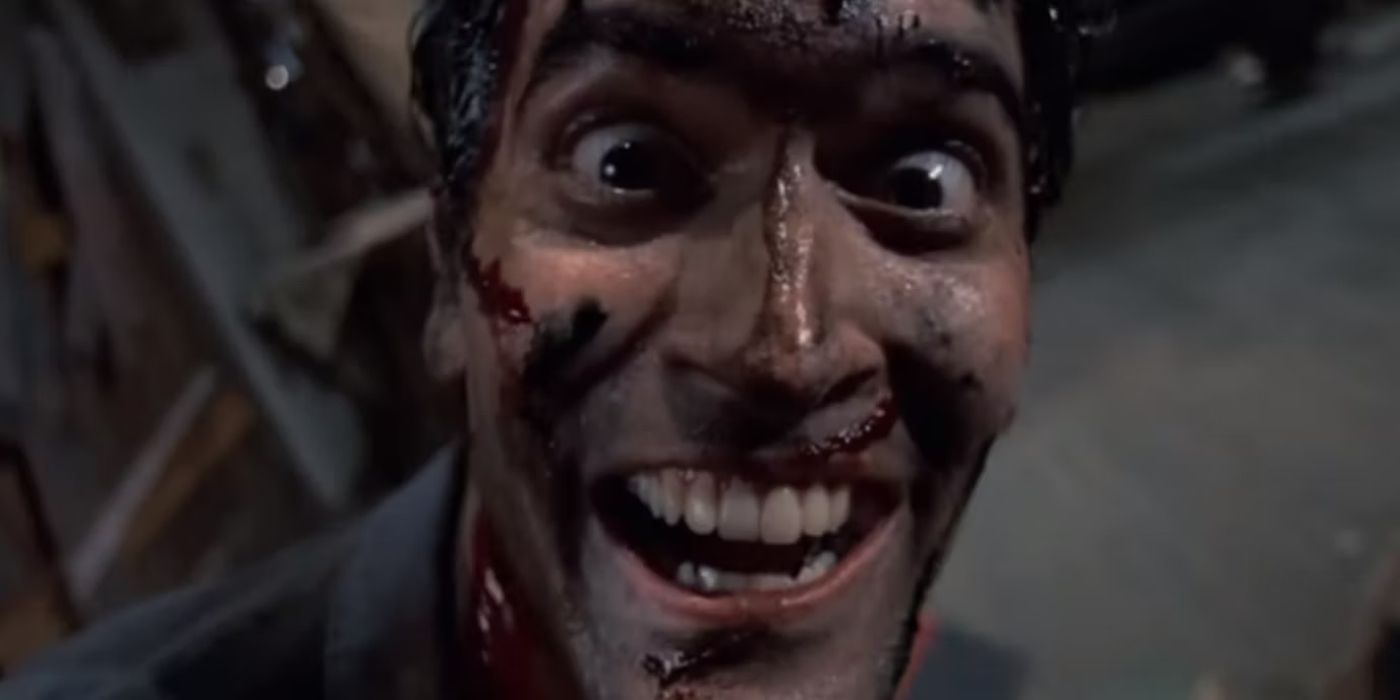 A bloody Ash Williams smiling maniacally in Evil Dead 2 while staring at the camera