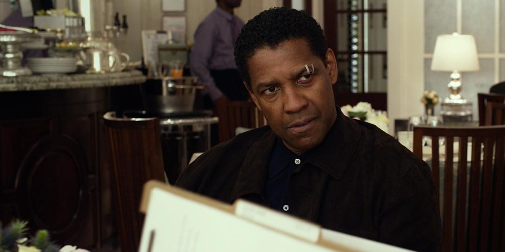 Denzel Washington com manchas na sobrancelha olhando com raiva para alguém fora da tela em voo.
