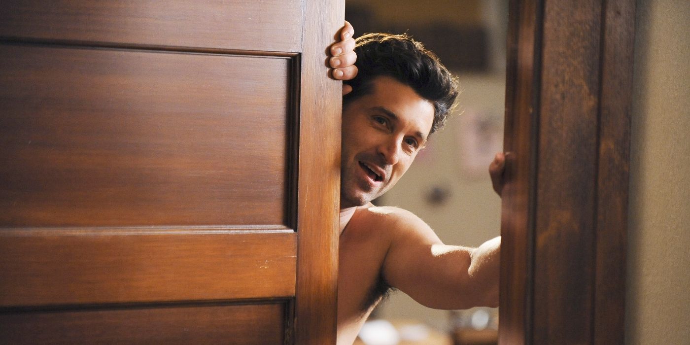 Patrick Dempsey as Derek Shepherd, shirtless and looking through a door, smiling in Grey's Anatomy