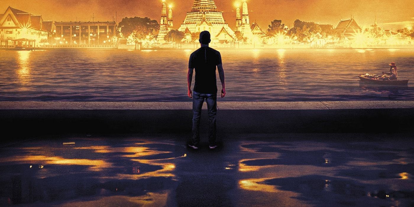 A man standing in water looking at a lit up waterfront town on the cover of Cockroaches by Joe Nesbø, a Harry Hole novel
