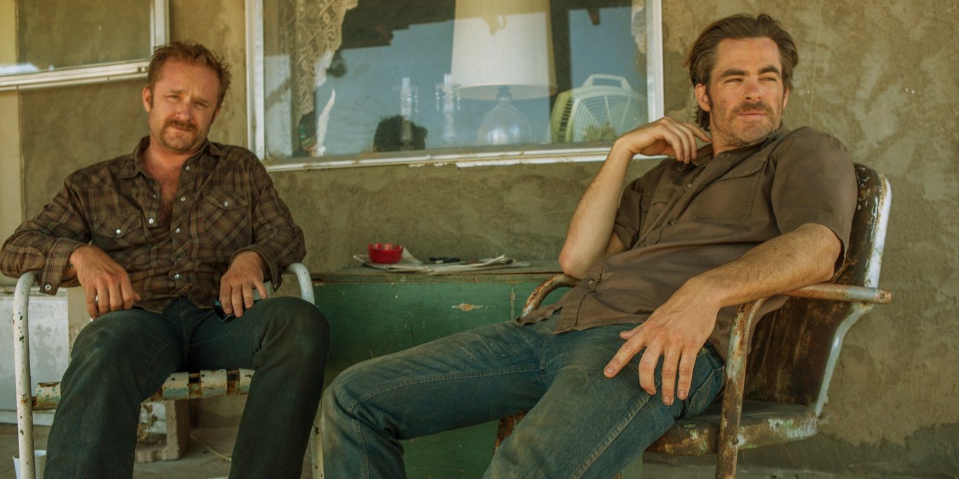 Chris Pine and Ben Foster sitting on their porch and looking at a person offscreen in 2016's Hell or High Water.