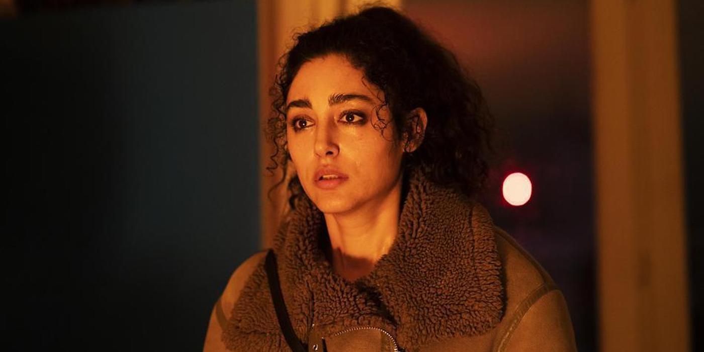 Golshifteh Farahani as Nour looking at a fire which is illuminating her face in Hood Witch. 