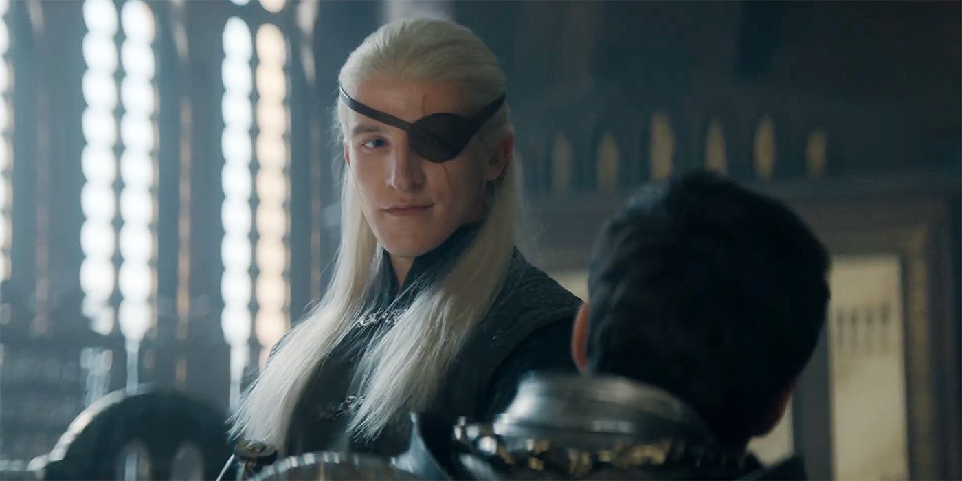 Ewan Mitchell as Aemond Targaryen looks down at someone seated in House of the Dragon Season 2