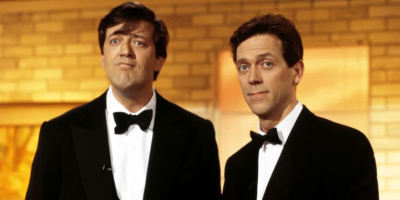 Hugh Laurie and Stephen Fry as themselves stand in tuxedos in front of a yellow brick background
