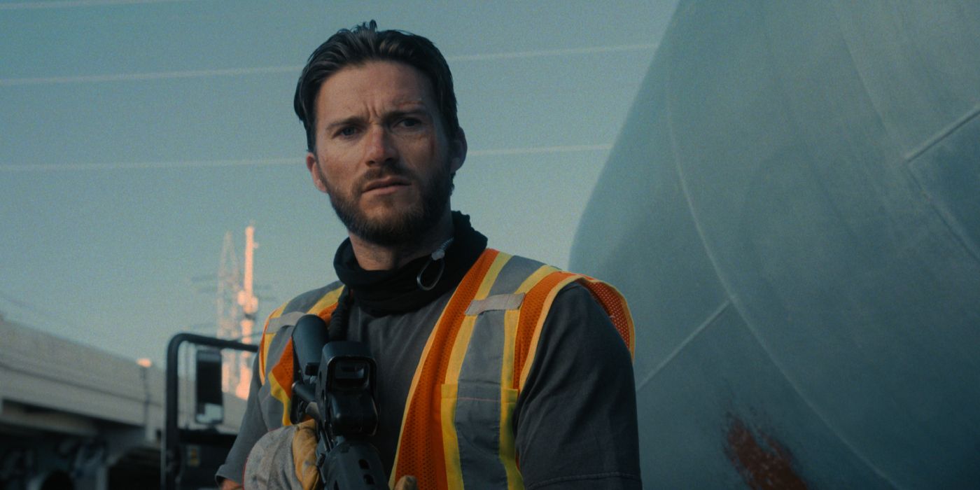 Jan (Scott Eastwood) stands in construction gear with a machine gun as he conducts a robbery in broad daylight in 'Wrath of Man' (2021)
