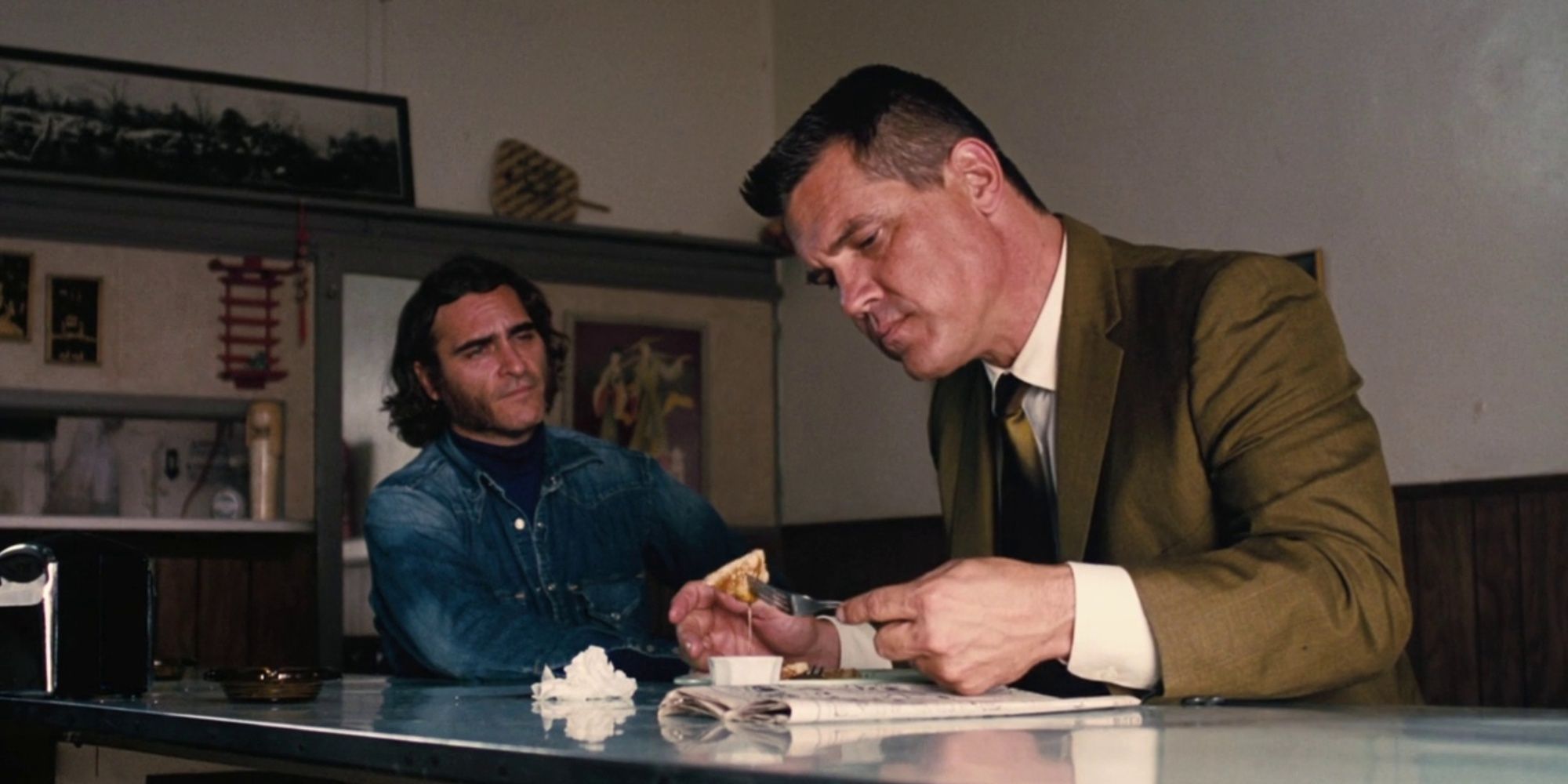 Joaquin Phoenix with Josh Brolin sitting at bench and eating in Inherent Vice